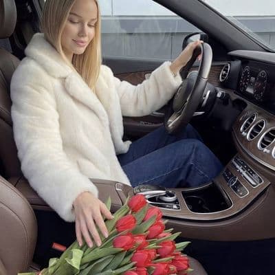 Фото девушки за рулём с букетом красных тюльпанов