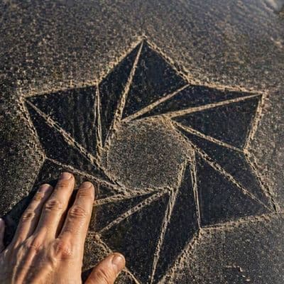 Логотип на капоте автомобиля, вытираемый рукой в пыли