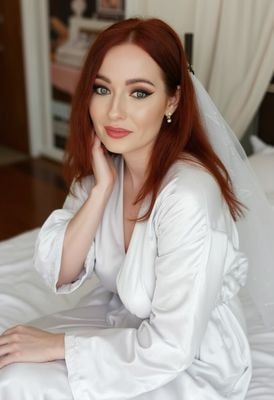 Невеста в атласном халате на кровати в номере отеля, свет справа